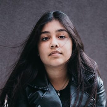 woman in black leather jacket and white pants sitting on white couch